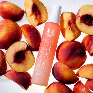 Peaches Hair And Body Fragrance Mist 100ml on white background surrounded by peaches.