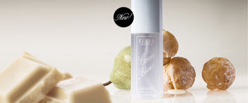 COCOA BLANCO Perfume Mist 90ml in front of pear and cream puffs and behind pile of white chocolate squares on gray background with black circle and white text that reads "New!"