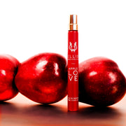 Apple Love 10ml Eau De Parfum Travel Spray on white table in front of apples, against white background.