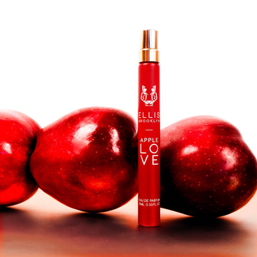 Spray de parfum de voyage Apple Love 10 ml sur une table blanche devant des pommes, sur un fond blanc.