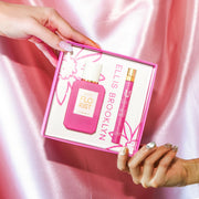 Modèle avec du vernis à ongles nude tenant le coin supérieur de la boîte du coffret cadeau Florist Eau De Parfum montrant Florist 50 ml Eau De Parfum et Florist 10 ml Eau De Parfum vaporisateur de voyage, et modèle avec du vernis à ongles gris irisé tenant le coin inférieur de la même boîte, sur fond de satin rose.
