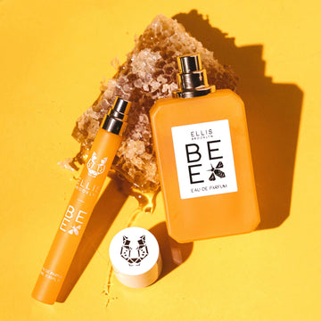 Spray voyage Bee 10ml Eau de Parfum sans bouchon et Bee 50ml Eau de Parfum sans bouchon posés sur un morceau de rayon de miel, sur fond jaune