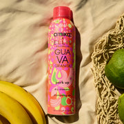 Amika x Ellis Brooklyn GUAVA GRANITA Shampooing sec Perk Up sur un tissu beige à côté de bananes, de goyaves et d’un sac tressé beige