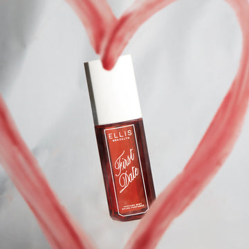 Brume Parfumée FIRST DATE 90ml sur fond gris entourée d’un cœur rouge dessiné au rouge à lèvres