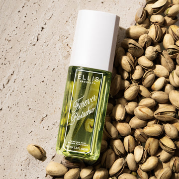 FOREVER PISTACHIO Perfume Mist 90ml on tan marble and pile of pistachios