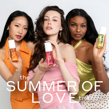 Woman with black hair wearing an orange dress and white pearl earrings holds NEW CRUSH Perfume Mist 90ml, woman with brown hair wearing a pink off the shoulder top and pink earrings holds LOVE POM Perfume Mist 90ml, and woman with brown hair wearing green tank top, gold bracelet and white and black polka dot skirt holds FOREVER PISTACHIO Perfume Mist 90ml on a white background with white text that reads 