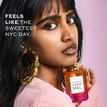 Woman with black hair wearing a pink sweater and gold hoop earrings that say 