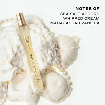 Vanilla Salt 10ml Eau De Parfum Travel Spray resting on whipped cream, vanilla ice cream, and pearl necklace, on white background next to black text that reads 
