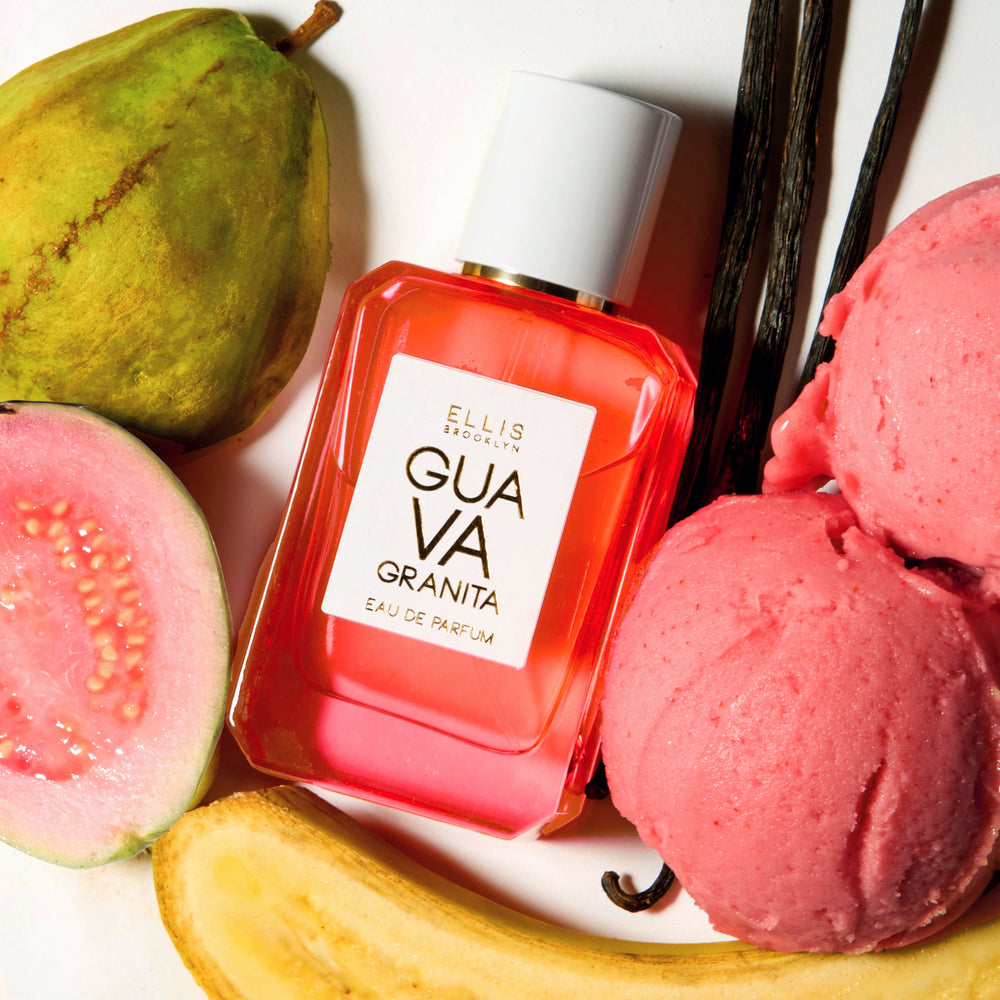 GUAVA GRANITA Eau de Parfum 50ml lays next to a guava, half a sliced guava, a sliced banana, two scoops of pink granita, and 3 vanilla beans on a white background | english_image