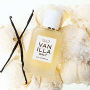 VANILLE SEL Eau de Parfum 50 ml repose sur des boules de glace à la vanille, des gousses de vanille et du sel sur un fond blanc