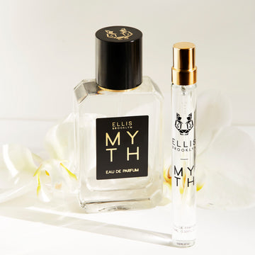 Myth 50 ml Eau de Parfum et Myth 10 ml Eau de Parfum vaporisateur de voyage devant des fleurs blanches sur fond blanc.