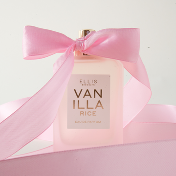 VANILLA RICE Eau de Parfum 50ml without cap with a pink bow tied around the atomizer and surrounded by pink ribbon on an off-white background
