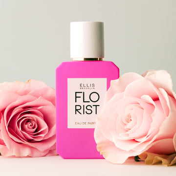 Flacon de parfum Florist 50 ml sur une table blanche avec des roses roses sur un fond blanc cassé.