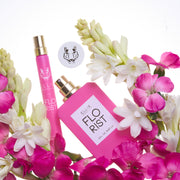 Parfum Florist 50ml Eau De Parfum avec le bouchon retiré et Parfum Florist 10ml Eau De Parfum en spray de voyage sur fond blanc entouré de fleurs roses et blanches.