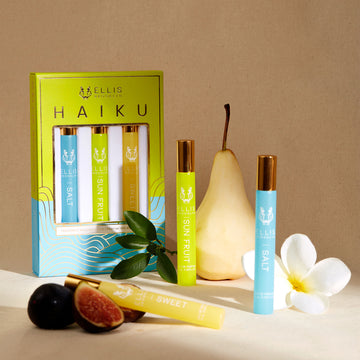 Boîte trio de roll-on parfum Haiku vert, bleu et or montrant le roll-on parfum Sel 10 ml, le roll-on parfum Fruit du Soleil 10 ml et le roll-on parfum Sweet 10 ml, sur fond blanc avec arrière-plan beige, avec le roll-on parfum Sel 10 ml, le roll-on parfum Fruit du Soleil 10 ml, le roll-on parfum Sweet 10 ml, poire, fleur blanche, figues et feuilles vertes.