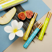 Coin de vert, bleu et or Boîte trio Haïku Fragrance Rollerball montrant Sweet 10ml Fragrance Rollerball, sur un fond beige et bleu avec un trait de pinceau noir, à côté de Salt 10ml Fragrance Rollerball, Sun Fruit 10ml Fragrance Rollerball, Sweet 10ml Fragrance Rollerball, poire, fleur blanche et figues.