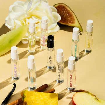 Dear Sky Eau De Parfum 1.5ml Vial, Miami Nectar Eau De Parfum 1.5ml Vial, Apple Love Eau De Parfum 1.5ml Vial, Salt Eau De Parfum 1.5ml Vial, Sun Fruit Eau De Parfum 1.5ml Vial, Florist Eau De Parfum 1.5ml Vial, Myth Eau De Parfum 1.5ml Vial, Sweet Eau De Parfum 1.5ml Vial, and Vanilla Milk Eau De Parfum 1.5ml Vial, on yellow background with fig, white flower, honeydew, vanilla bean, sandalwood, pineapple, and apple. | english_image