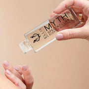 Mannequin avec du vernis à ongles nude portant des bagues en or tenant le Model tenant l'Huile Corporelle Parfumée Spectaculaire Myth 95 ml sans le bouchon dans une main tout en versant le produit sur l'autre main.