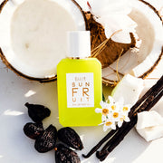 Sun Fruit 50ml Eau de Parfum appuyé sur une noix de coco ouverte à côté de fleurs blanches, de gousses de vanille, de morceaux de noix de coco et de figues sèches, sur fond blanc.