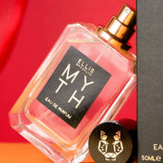 Myth 50 ml Eau de Parfum avec le bouchon retiré, appuyé sur la boîte de Myth 50 ml Eau de Parfum, sur un fond rouge et orange.
