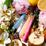 Salt 10ml Eau De Parfum Travel Spray,  Myth 10ml Eau De Parfum Travel Spray, Vanilla Milk 10ml Eau De Parfum Travel Spray, and Florist 10ml Eau De Parfum Travel Spray on white background surrounded by bergamot, lemons, pink flowers, white flowers, yellow flowers, pears, green leaves, sandal wood, and vanilla beans.