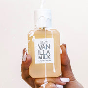 Model with white nail polish holding Vanilla Milk 50ml Eau De Parfum with milk being poured on bottle and hand on white background.