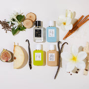 Myth 7.5ml Eau De Parfum Mini Dabber, Salt 7.5ml Eau De Parfum Mini Dabber, Sun Fruit 7.5ml Eau De Parfum Mini Dabber, and Vanilla Milk 7.5ml Eau De Parfum Mini Dabber surrounded by white flowers, cedar wood, ambrette seeds, sandal wood, sea salt, vanilla beans, cocoa shells, pear, and fig, on white background.