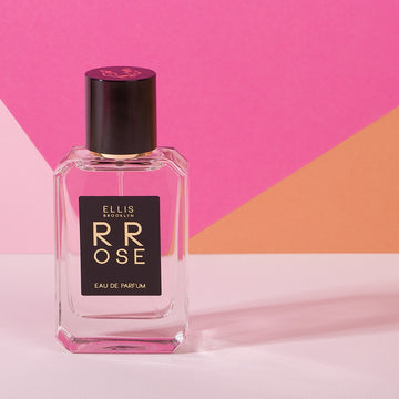 Rrose 50ml Eau De Parfum on light pink table against light pink, dark pink, and orange background.