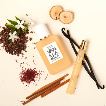 Vanilla Milk 50ml Eau De Parfum and Vanilla Milk 10ml Eau De Parfum Travel Spray on off-white background with vanilla beans, sandalwood, white flowers, and cocoa shells.