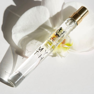 Myth 10ml Eau De Parfum Travel Spray resting on white orchid flower on white background.