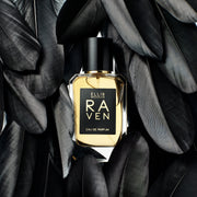 Raven 50ml Eau De Parfum on white background, surrounded by black bird feathers.