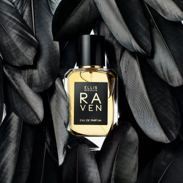 Raven 50ml Eau De Parfum on white background, surrounded by black bird feathers.