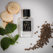 Myth 7.5ml Eau De Parfum Mini Dabber on white background with sandal wood, green leaves and ambrette seeds.