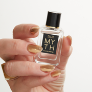 Model with gold nail polish wearing gold ring holding Myth 7.5ml Eau De Parfum Mini Dabber on white background.